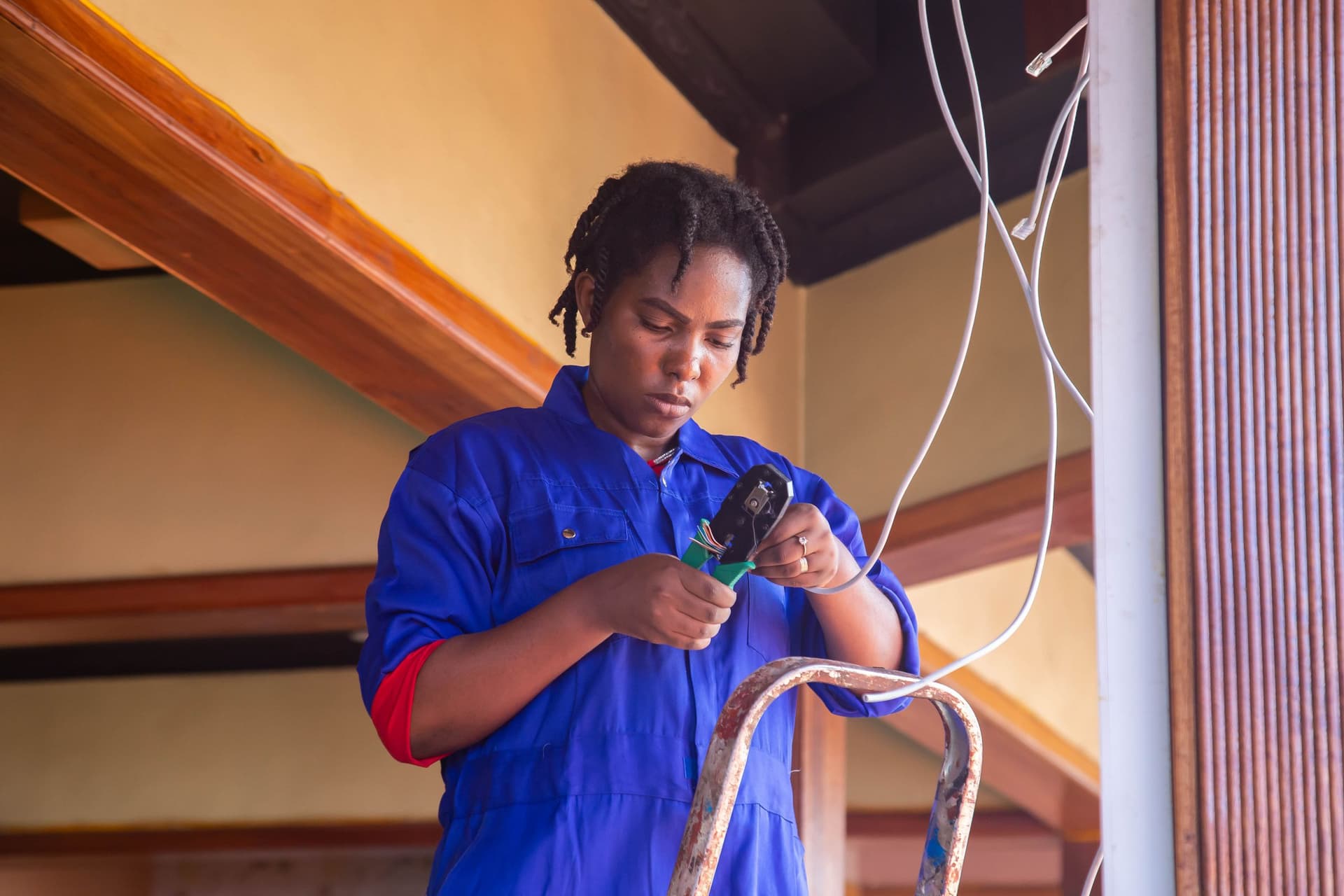 Technician crimping a data cable on a ladder