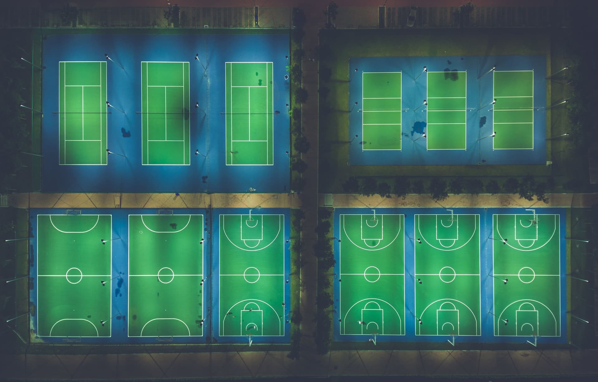 Aerial view of floodlit sports courts at night
