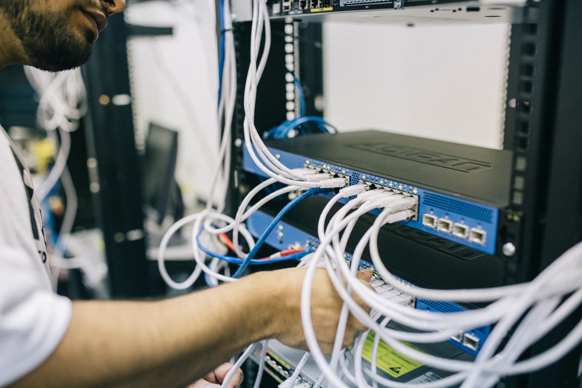 Technician patching network cables in a comms rack