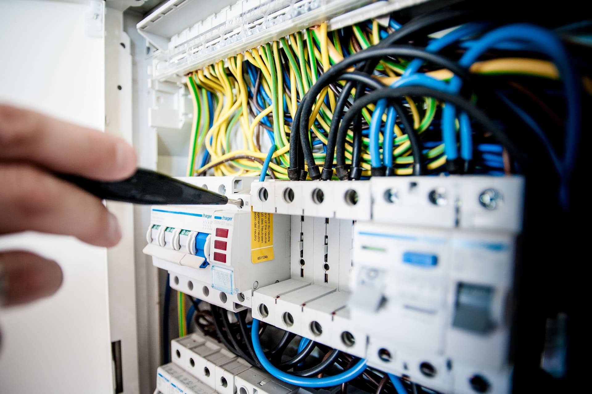 Electrician working on a switchboard with safety switches and circuit breakers